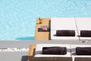 2 sillones blancos junto a la piscina en Dreambox Mykonos Suites, en Ornos