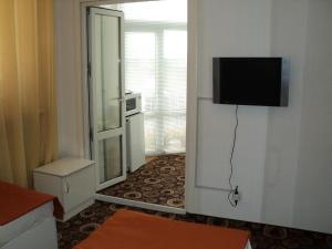 a room with a television on a wall with a door at Guest House Valentino in Krasnodar