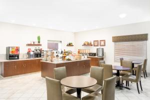 a restaurant with tables and chairs and a kitchen at Ramada by Wyndham Olds in Olds