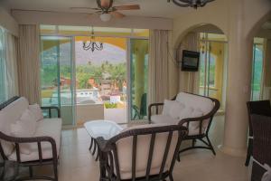 a living room with white chairs and a balcony at Bungalows Arena Dorada in Zihuatanejo