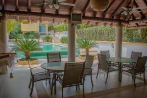 a patio with tables and chairs and a swimming pool at Bungalows Arena Dorada in Zihuatanejo