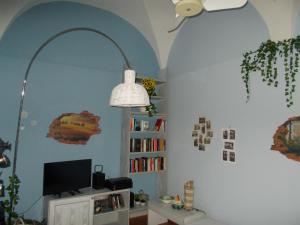 Zimmer mit einem TV und einem Regal mit Büchern in der Unterkunft “La Loggia” Apartment in Casale Monferrato