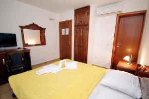 a bedroom with a yellow bed with towels on it at Apartmani More in Sveti Stefan