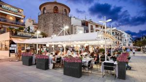 a group of people sitting at tables in front of a building at Apartaments Cambrils Suite Costa Daurada in Cambrils
