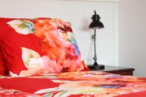 a red bed with a flower pillow and a lamp at Gastenverblijf Kleinkamperfoelie in Gorssel