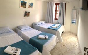 a room with three beds and a window at Hospedaria Aconchego in Santa Teresa