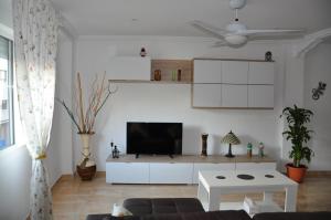 sala de estar con TV en una pared blanca en Alenia Apartments, en Alicante