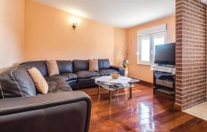 Una sala de estar con un sofá de cuero y un televisor. en Apartman Relax, en Podstrana