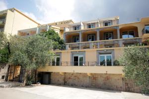an apartment building with a tree in front of it at Apartmani More in Sveti Stefan