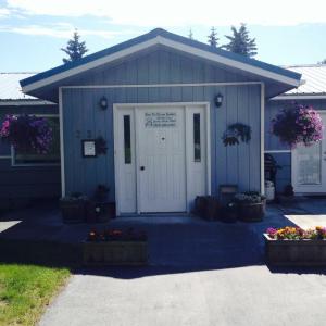 a blue building with a white door and some flowers at Bears Den Alaska Lodging in Seward