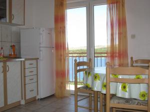 a kitchen with a table and a refrigerator and a balcony at Apartments Šparada Mladen in Grebaštica
