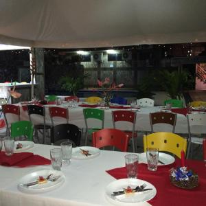 un comedor con mesas blancas y sillas coloridas en Hotel Joya de la Selva en Tena