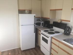 a kitchen with a white refrigerator and a stove at Gillies by the Sea Apartment and Suite in Port Hood