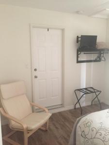 um quarto com uma porta branca, uma cadeira e uma cama em Gillies by the Sea Apartment and Suite em Port Hood