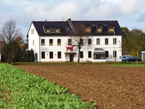 ein weißes Haus mit einem schwarzen Dach und einem Feld in der Unterkunft Hotel-Restaurant Rotes Einhorn Düren *** Superior in Düren - Eifel