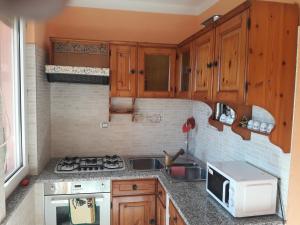 una cucina con armadi in legno, lavandino e forno a microonde di Welcome House a Olbia