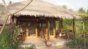 une cabane avec un toit de paille, une table et des chaises dans l'établissement Bale Jukung, à Tanjung