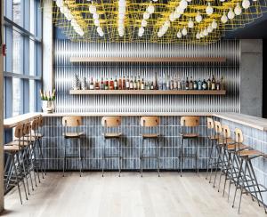 a bar with a bunch of stools in a room at Boro Hotel in Queens