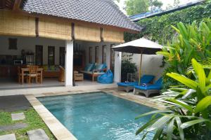 a pool in front of a house with an umbrella at Villa Mewali in Ubud