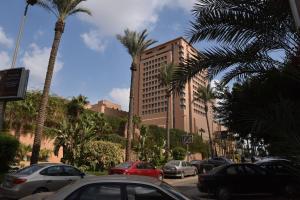 a street with cars parked in front of a tall building at Fancy apartment in front of City Stars in Cairo