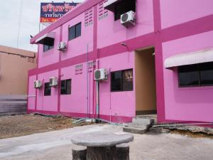 a pink building with a bench in front of it at Charinsup Hotel in Ban Khlong Thai Muang
