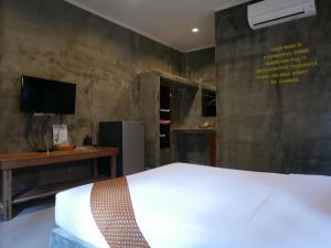 ein Schlafzimmer mit einem Bett, einem Schreibtisch und einem Fernseher in der Unterkunft Le Pes Villas in Khanom