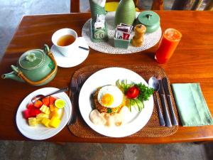 a table with two plates of breakfast food and a cup of coffee at Puri Dajuma Villas in Pulukan