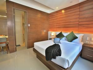 a bedroom with a bed with a laptop on it at Valero Grand Suites by Swiss-Belhotel in Manila