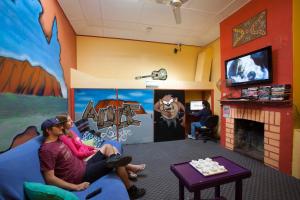 a man and woman sitting on a couch in a room with a fireplace at Alice Lodge in Alice Springs