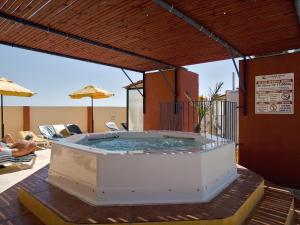 Canifor Hotel في خليج سانت بول: حوض استحمام ساخن على فناء مع مظلة