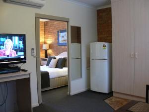 Habitación con cama, nevera y TV. en Begonia City Motor Inn, en Ballarat