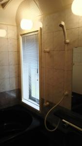 La salle de bains est pourvue d'une fenêtre, d'un lavabo et d'une douche. dans l'établissement Guest House Koundo, à Nikkō