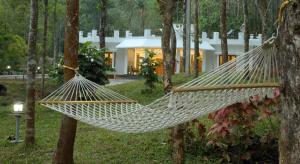 a hammock in front of a house at L&G Riverview Haven. in Vandiperiyār