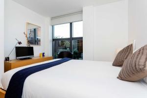 a bedroom with a large white bed and a television at Veeve - Zen By The Water in London
