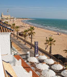a view of a beach with umbrellas and the ocean at Hotel Playa de Regla in Chipiona