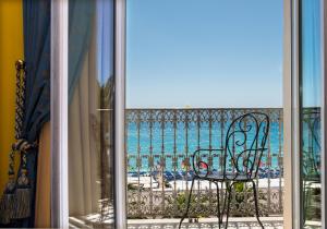 a bench on a balcony looking out at the ocean at Hôtel West End Promenade in Nice