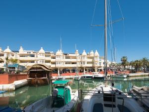 dwie łodzie zacumowane w przystani z dużym budynkiem w obiekcie Puerto Marina Beach & Golf w mieście Benalmádena