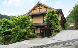 una casa en una calle con árboles delante de ella en Yunohira Kamiyanagiya en Yufuin