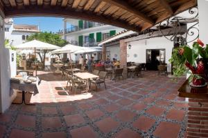 un patio al aire libre con mesas, sillas y sombrillas en L´Hostalet en Tossa de Mar