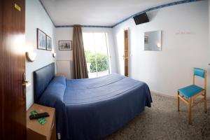 1 dormitorio con 1 cama azul y 1 silla en L´Hostalet, en Tossa de Mar