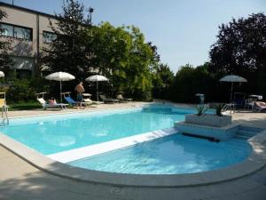 a large blue swimming pool with umbrellas and a building at San Paolo Hotel in Montegiorgio