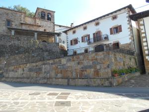 a stone wall in front of two buildings at Casa Rural Juankonogoia in Urrotz