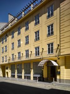 a yellow building with balconies on a street at K+K Hotel Maria Theresia in Vienna