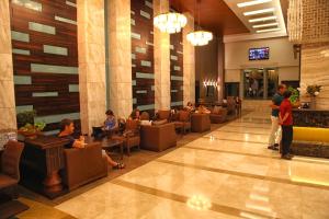 a lobby of a hotel with people sitting in chairs at Queen's Park Le Jardin in Kemer