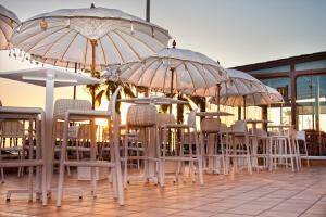 un grupo de mesas y sillas con sombrillas en Hotel Playa de Regla, en Chipiona