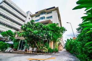 budynek z krzesłami i drzewami przed nim w obiekcie Kanavera Sriracha Hotel & Serviced Apartment w mieście Si Racha