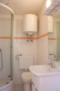 a bathroom with a toilet and a sink and a mirror at Apartments Alaburic in Pag