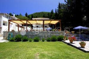 a backyard with a stone wall and an umbrella at Geni Garden Apartments in Yénion