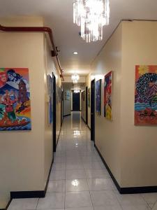 a hallway in a building with paintings on the walls at City Corner Hotel in Legazpi