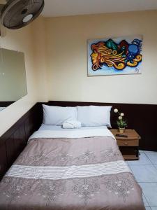 a bed in a bedroom with a painting on the wall at City Corner Hotel in Legazpi